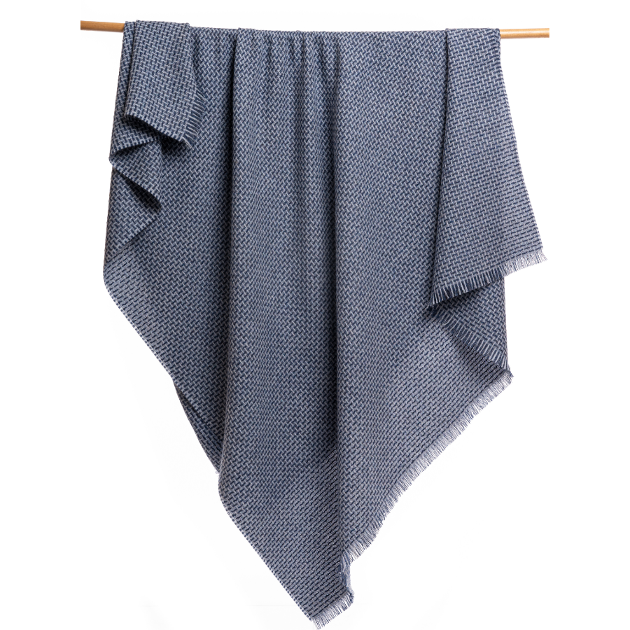 An Alpacas of Montana soft cozy luxury warm light blue and navy woven blanket with a tasseled edge.