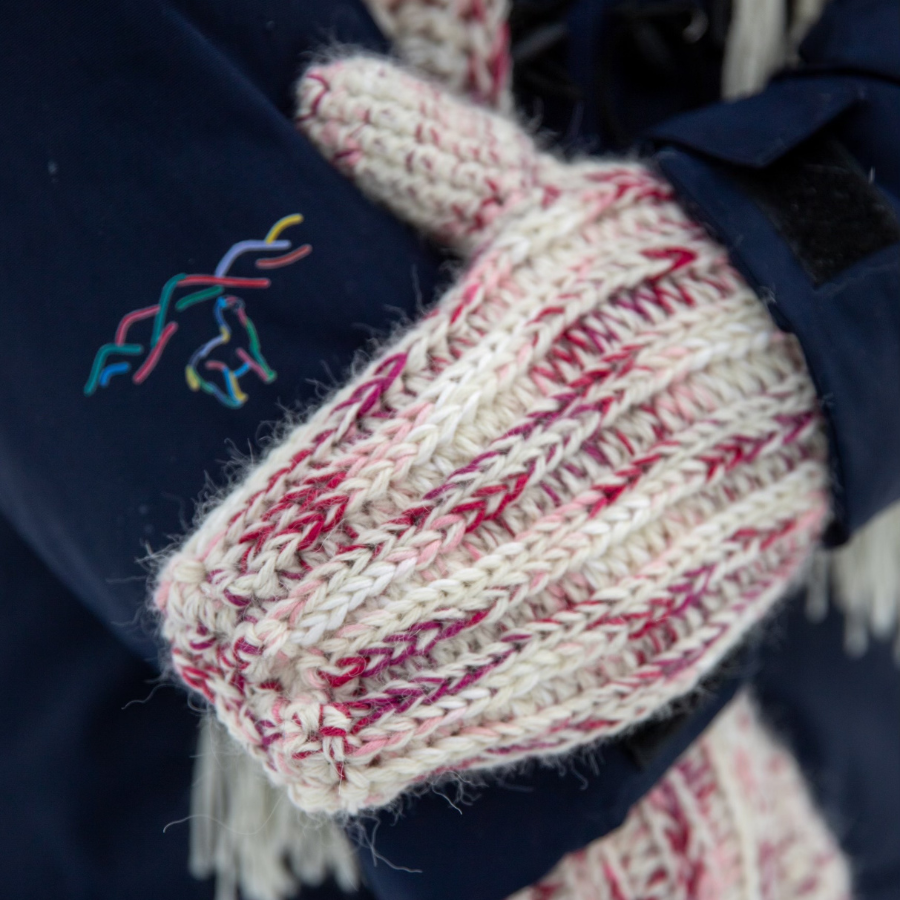 A close up photograph of the warm cozy handmade knit crochet Alpacas of Montana ribbed mittens, a mixture of the colors fuchsia, dark pink, light pink, carnation, and white.