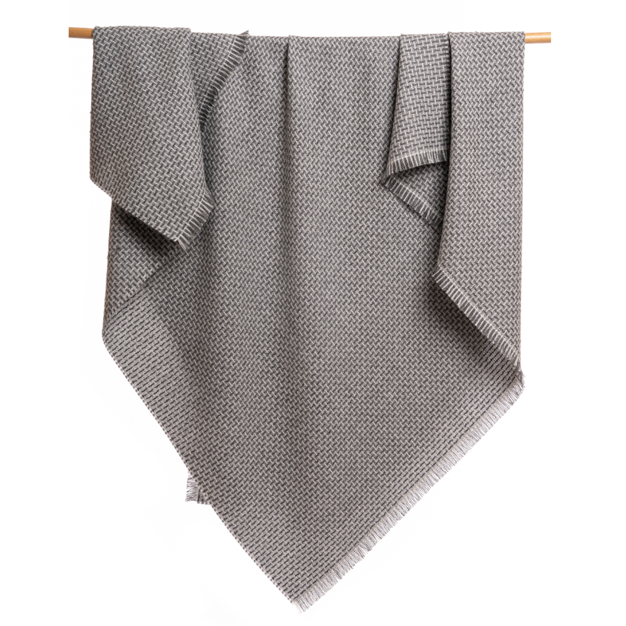 An Alpacas of Montana soft cozy luxury warm dark charcoal gray and light gray woven blanket with a tasseled edge.