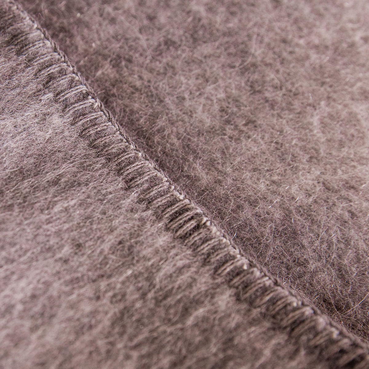 A close up shot of a medium gray Alpacas of Montana soft warm thermal moisture wicking lightweight plush king or queen size alpaca wool blanket.