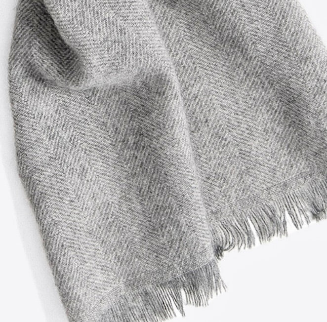 A close up product photo with a white background of a soft cozy stylish comfortable women&#39;s fashion moisture wicking warm cute lovely herringbone patterned gray alpaca wool scarf.