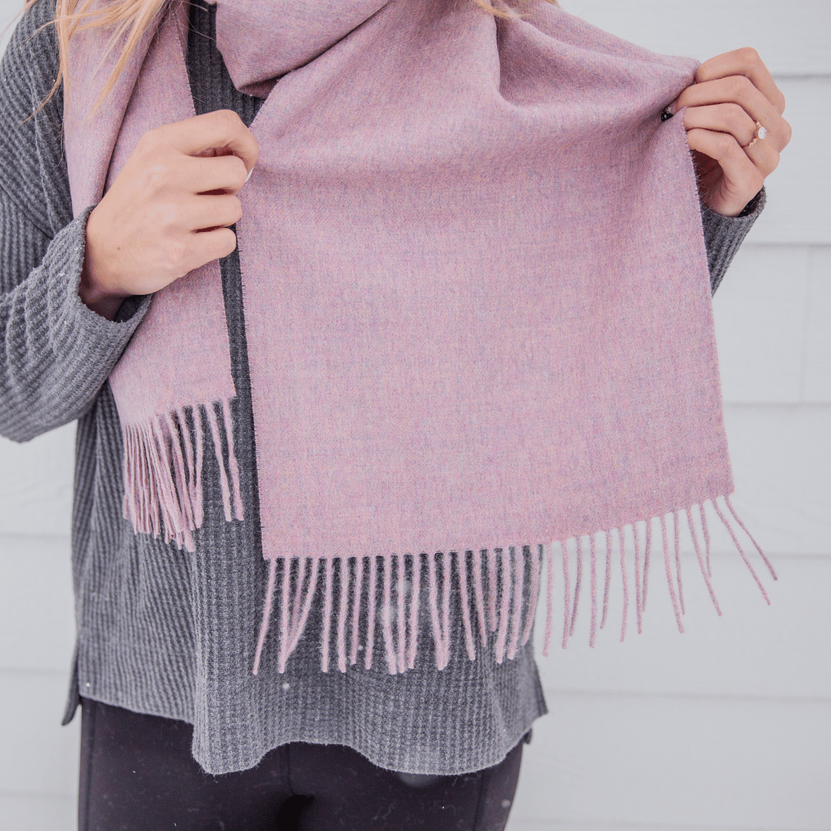 A close up of an Alpacas of Montana soft stylish women&#39;s fashion comfortable cozy cute warm alpaca wool soft pink blush color solid woven scarf with tassels.