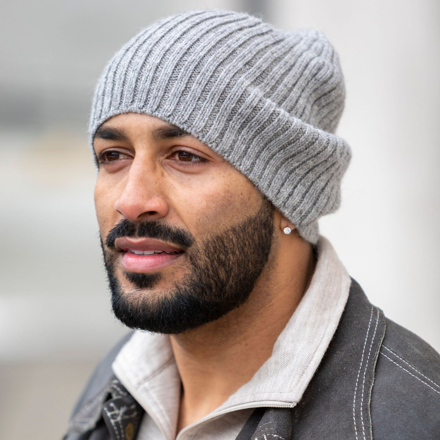 A close up photo of a man with a black beard wearing the soft warm winter cozy moisture wicking comfortable fashionable light gray alpaca wool ribbed beartooth beanie.