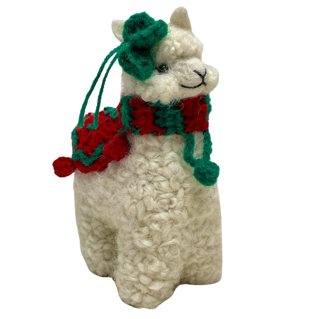 A product photo of a cute soft fluffy handmade toy natural white alpaca with a green flower on its head and a red and green scarf and blanket felted woven alpaca wool figurine and ornament for christmas holiday gifts