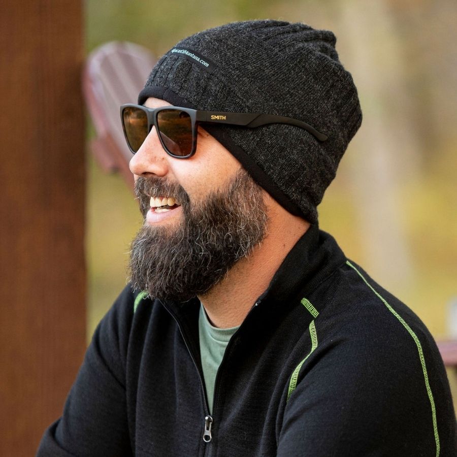 A man smiling wearing sunglasses and a black alpaca wool charcoal gray backcountry beanie