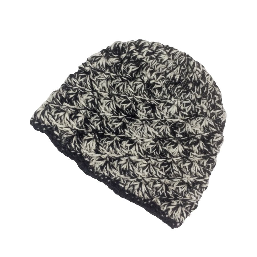 A product photo with a white background of a soft stylish cozy comfortable fashionable moisture wicking knitted crochet scallop pattern hat handmade in Montana from black and natural white alpaca wool.
