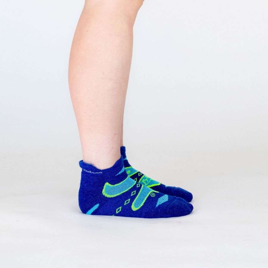 A side view of a person&#39;s lower legs against a white background of the Alpacas of Montana soft comfortable breathable athletic outerwear activewear moisture wicking blue, cyan, and lime yellow green endurance sock for running, sports, hiking, exercise.