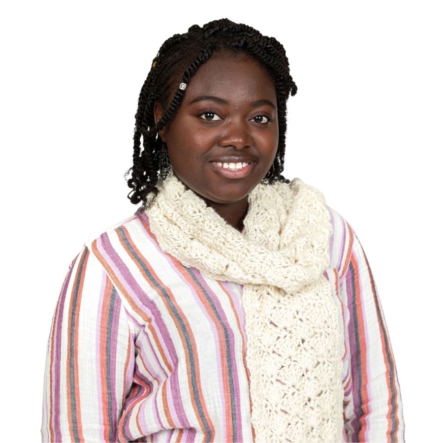 A black woman standing against a white background wearing a pink, white, and orange vertical stripe shirt and a soft stylish cozy comfortable fashionable moisture wicking knitted crochet scallop pattern scarf handmade in Montana from natural white alpaca wool and bamboo yarn.