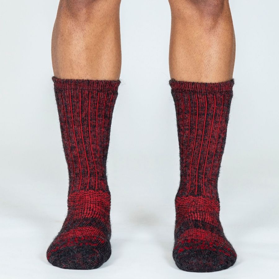 A front view of a person&#39;s lower legs wearing the Alpacas of Montana cozy soft warm comfortable thermal moisture wicking everyday winter fishing hiking snowshoeing hunting outdoors scarlet and black wine red extra cushion boot socks.
