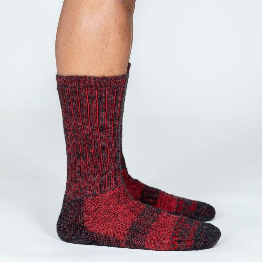 A side view of a person&#39;s lower legs wearing Alpacas of Montana cozy soft warm comfortable thermal moisture wicking everyday winter fishing hiking snowshoeing hunting outdoors scarlet and black wine red extra cushion boot socks.