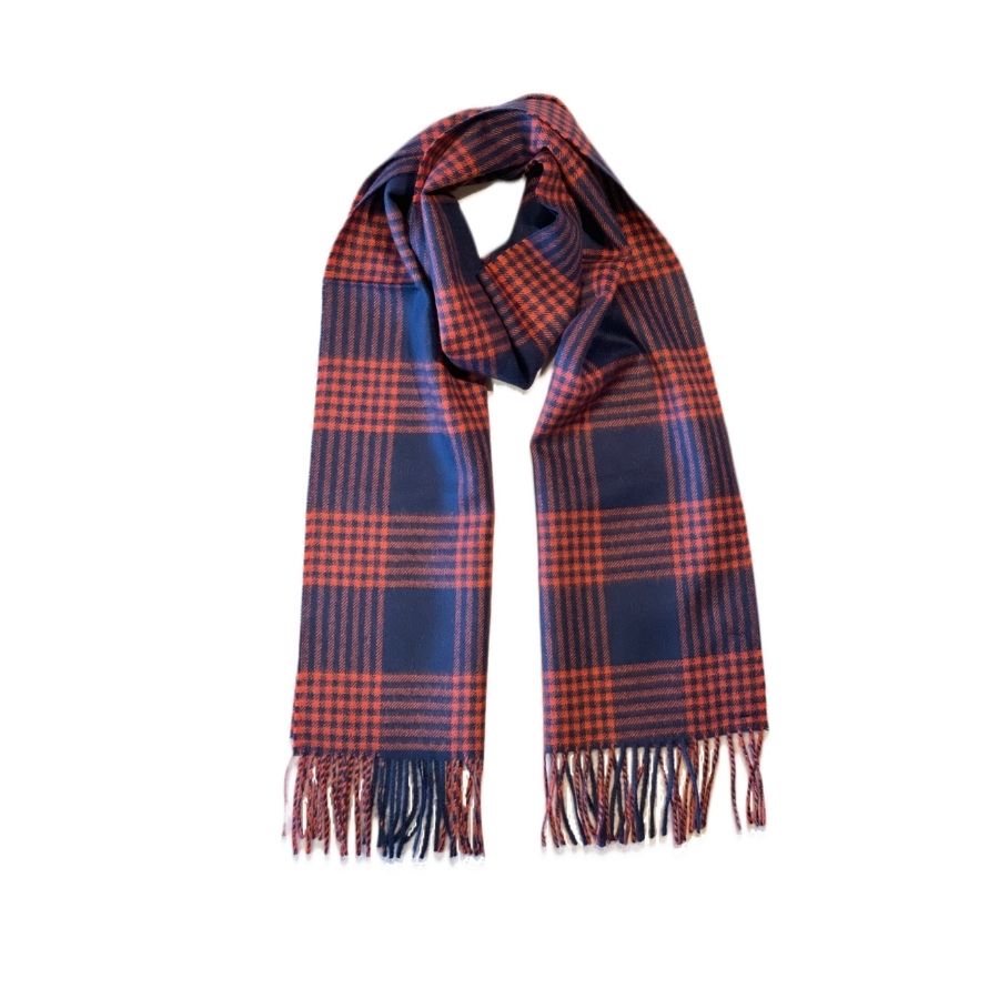 A product photo against a white background of an Alpacas of Montana soft stylish women&#39;s fashion comfortable cozy cute warm alpaca wool orange red and navy blue plaid pattern scarf with tassels.