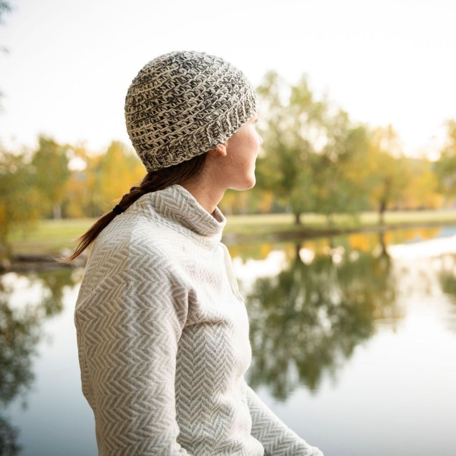woman looking into the distance wearing gray white and black hand knit alpaca wool hat