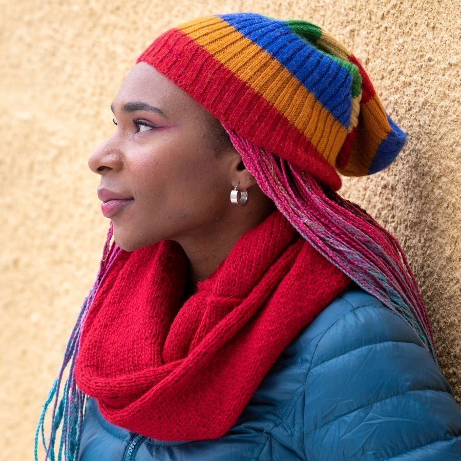 Side profile photo of a black woman wearing rainbow colored soft warm winter cozy moisture wicking comfortable fashionable alpaca wool ribbed alpaca wool beartooth beanie hat