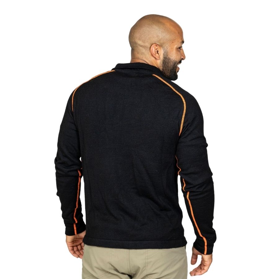 A smiling bald man with a black beard standing facing away from the camera in front of a white background. He is wearing khaki pants and a black with orange stitching Alpacas of Montana warm thermal soft cozy comfortable activewear outerwear athletic moisture wicking antimicrobial men&#39;s fashion stylish luxury mid-layer quarter-zip alpaca wool long sleeve pullover top for outdoors camping climbing hiking skiing hunting fishing running winter.