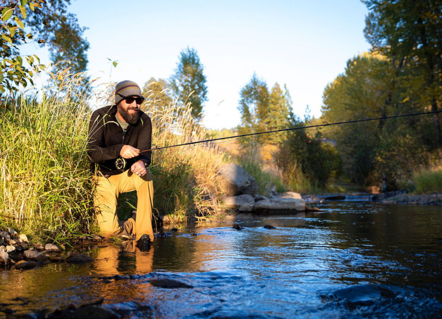 man fly fishing wearing black and green alpaca wool mid layer pullover and gray green and purple backcountry beanie hat
