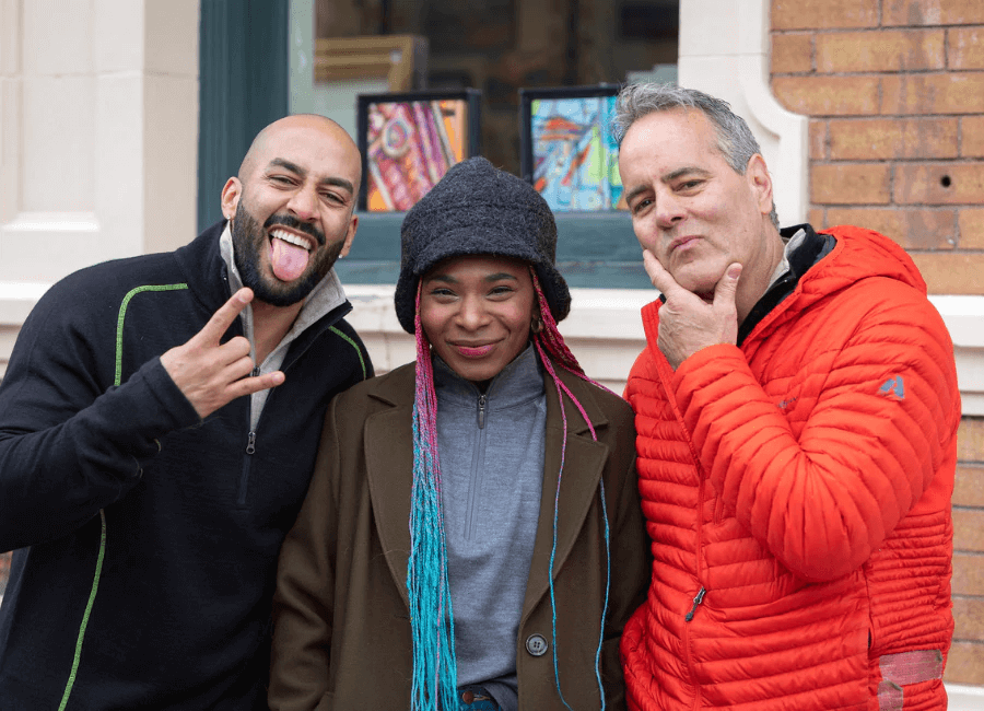 a hispanic man, a black woman and a white man standing together smiling