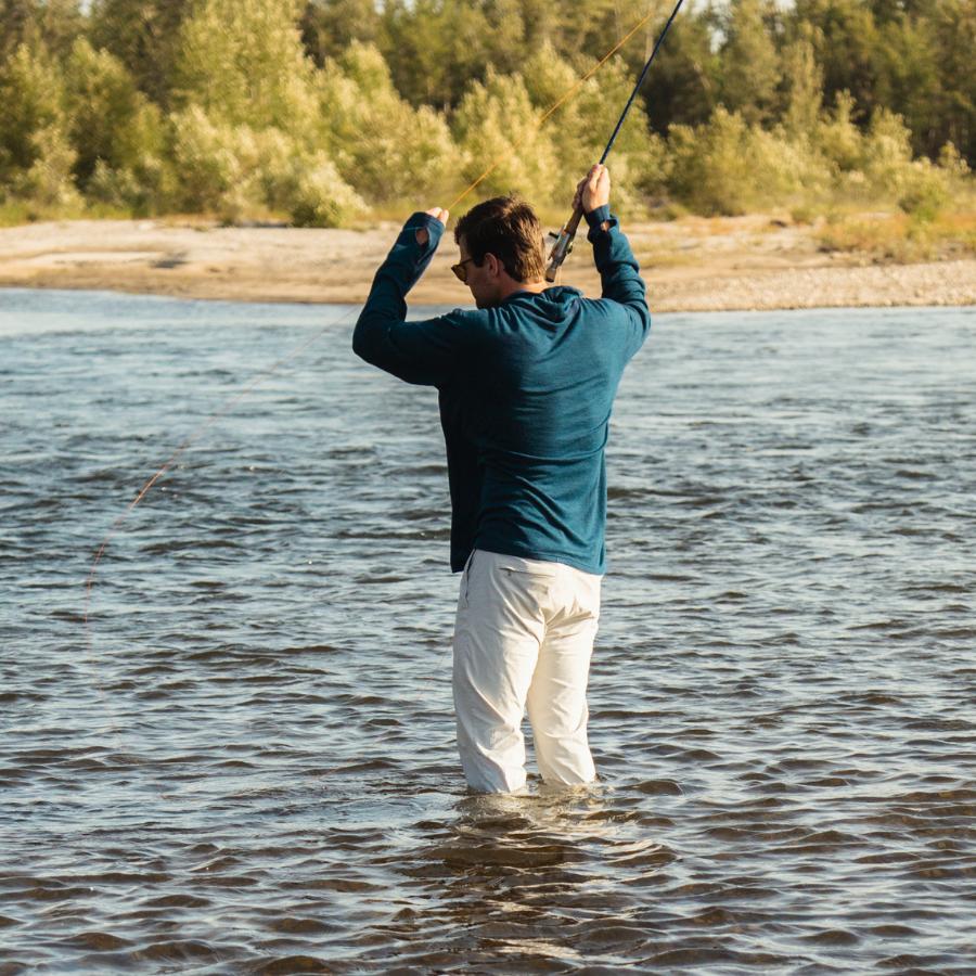 woman fly fishing in a river wearing a black and red alpaca wool mid layer and a warm alpaca beartooth beanie hat