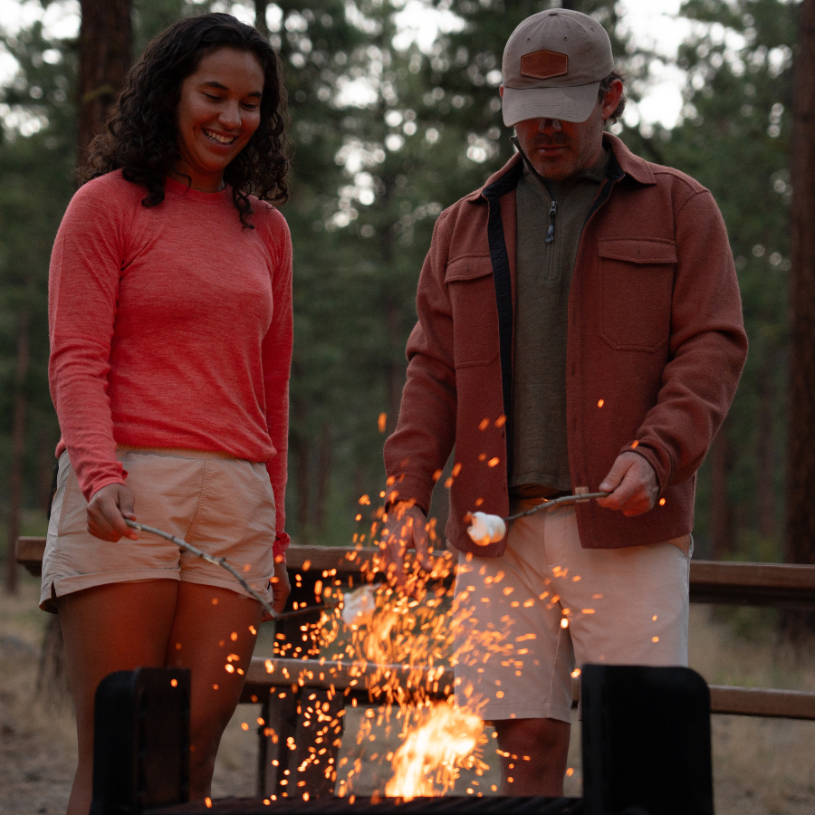 man and woman sitting in a tent smiling at each other wearing alpacas of montana base layers and socks