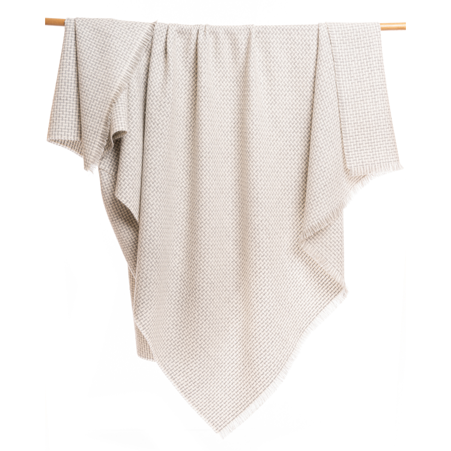 An Alpacas of Montana soft cozy luxury warm light gray and natural white woven blanket with a tasseled edge.