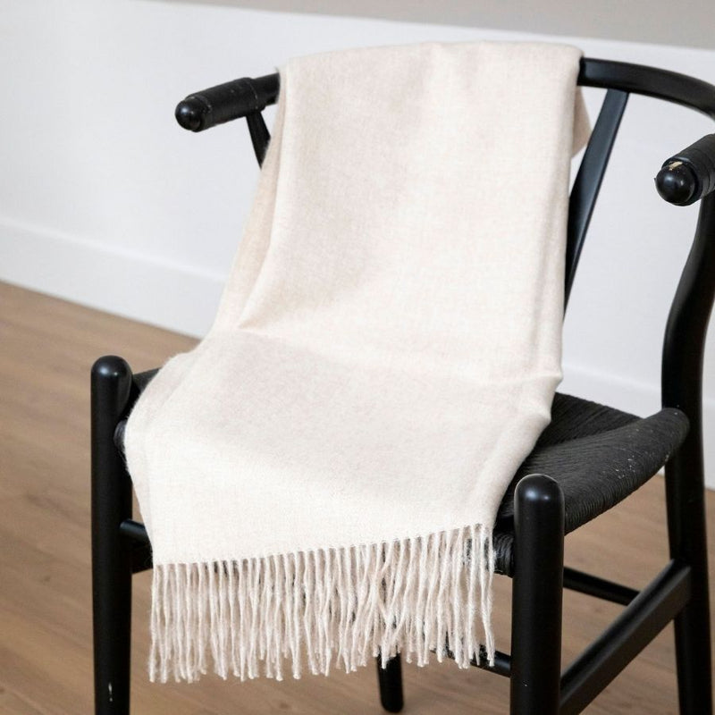 White Alpaca blanket laid on a black wooden chair