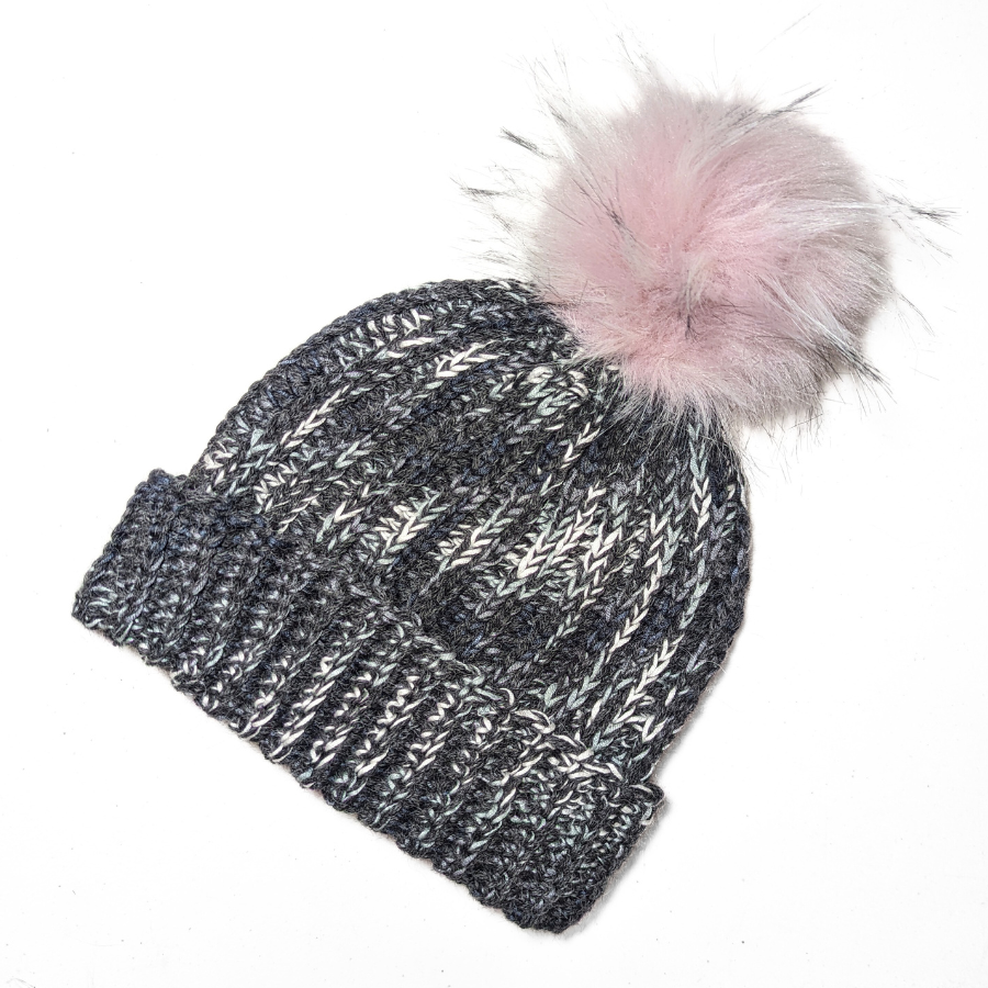Black, charcoal, dark gray, light gray, and white colored cozy soft warm handmade knitted crochet ridge ribbed hat with a light pink pom pom made in Montana by Alpacas of Montana.