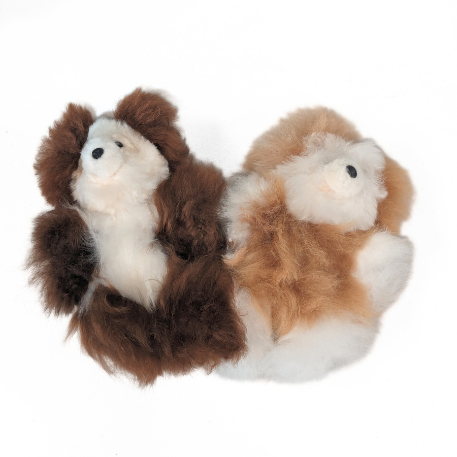 A product photo with a white background of two Alpacas of Montana soft fluffy cozy cute adorable toy silky luxury royal alpaca teddy bear plushie figurine for gifts birthdays christmas children present. The one on the left is cocoa chocolate brown and white, the one on the right is tan fawn brown and white.
