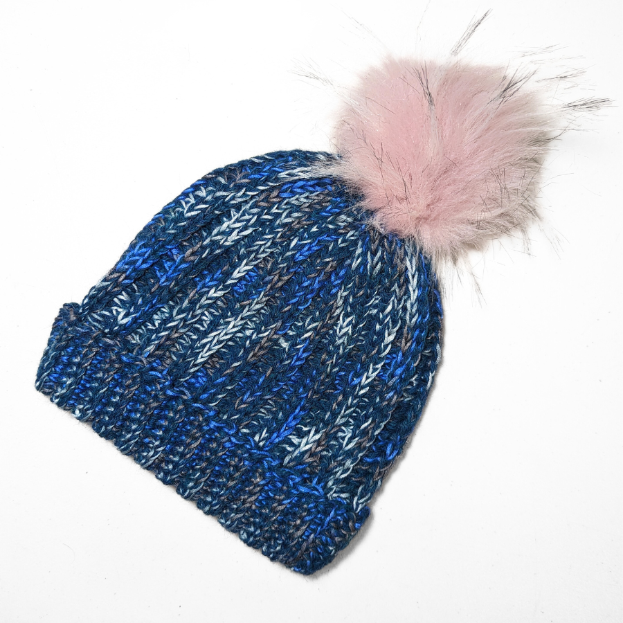 Ocean blue, dark turquoise, cobalt, cerulean, gray, and white colored cozy soft warm handmade knitted crochet ridge ribbed hat with a light pink pom pom made in Montana by Alpacas of Montana.