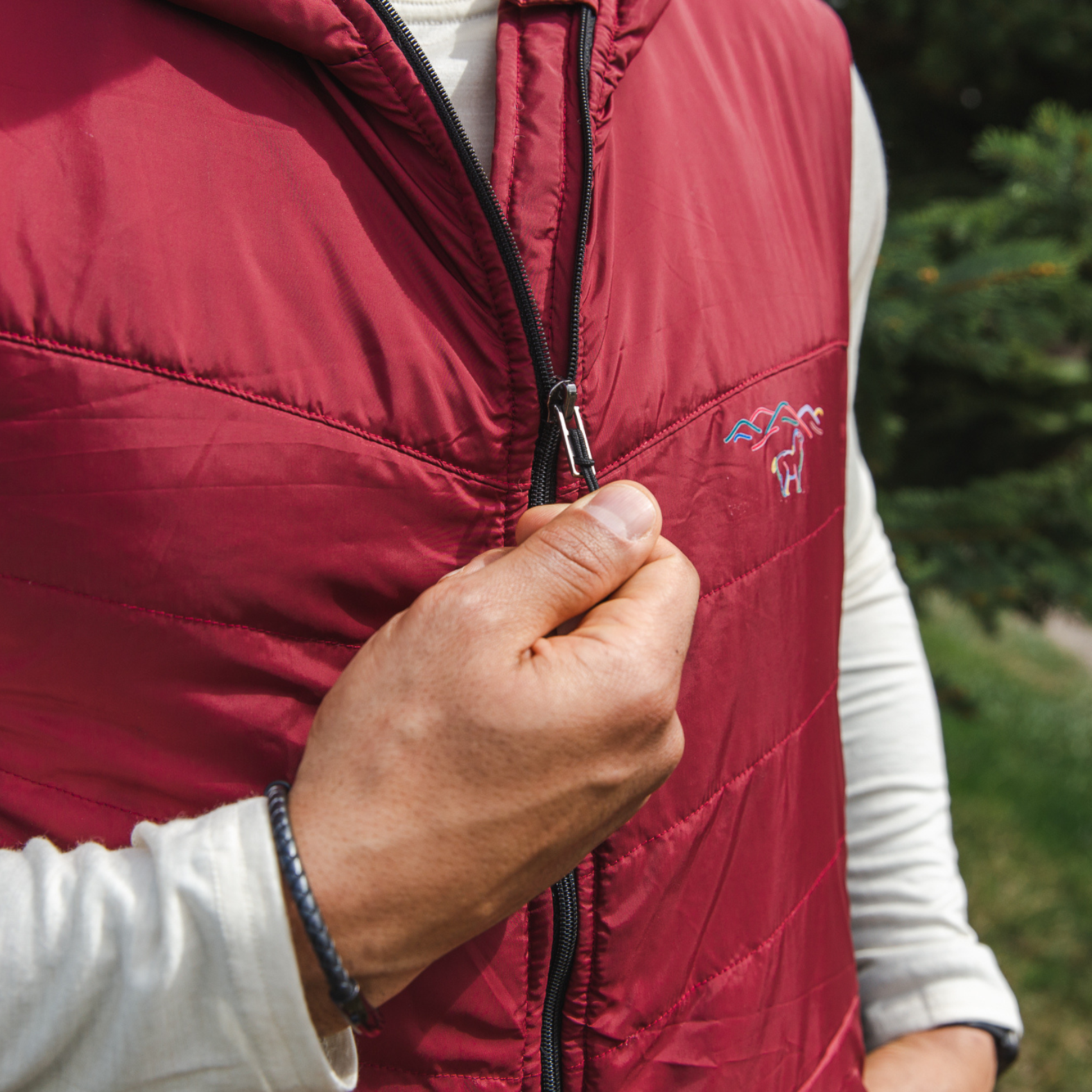 A close up photo of the zipper of a cranberry red Alpacas of Montana lightweight athletic activewear outerwear breathable moisture wicking antimicrobial soft comfortable exercise alpaca men's stretch lite vest for running sports exercise work out hiking climbing camping biking