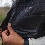 A close up photo of the logo and detailing on a black Alpacas of Montana lightweight athletic activewear outerwear breathable moisture wicking antimicrobial soft comfortable exercise alpaca men's stretch lite vest for running sports exercise work out hiking climbing camping biking