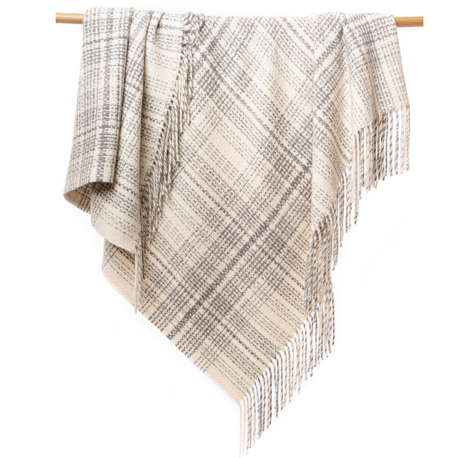 An Alpacas of Montana soft cozy luxury warm natural white with gray accent heather plaid blanket with a tasseled edge.