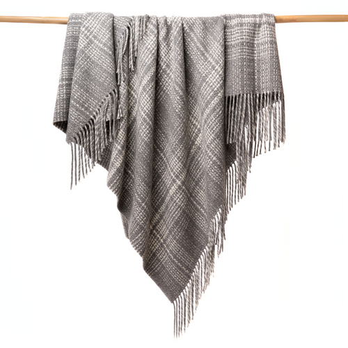 Gray plaid blanket with fringe draped over a wooden rod on a white background