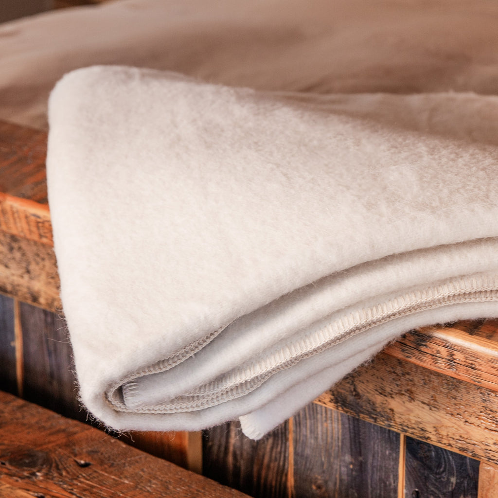 A close up shot of a natural white Alpacas of Montana soft warm thermal moisture wicking lightweight plush king or queen size alpaca wool blanket.