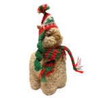 Plush toy llama wearing a festive hat and scarf on a white background