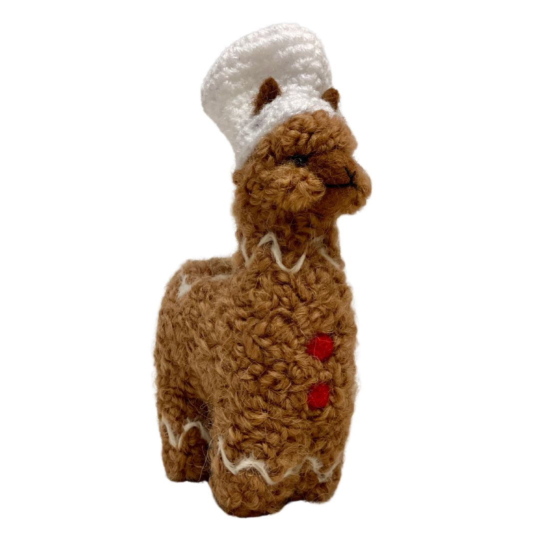 A soft cute adorable fluffy gingerbread alpaca with red buttons and a white chef hat figurine and ornament made from real alpaca wool yarn