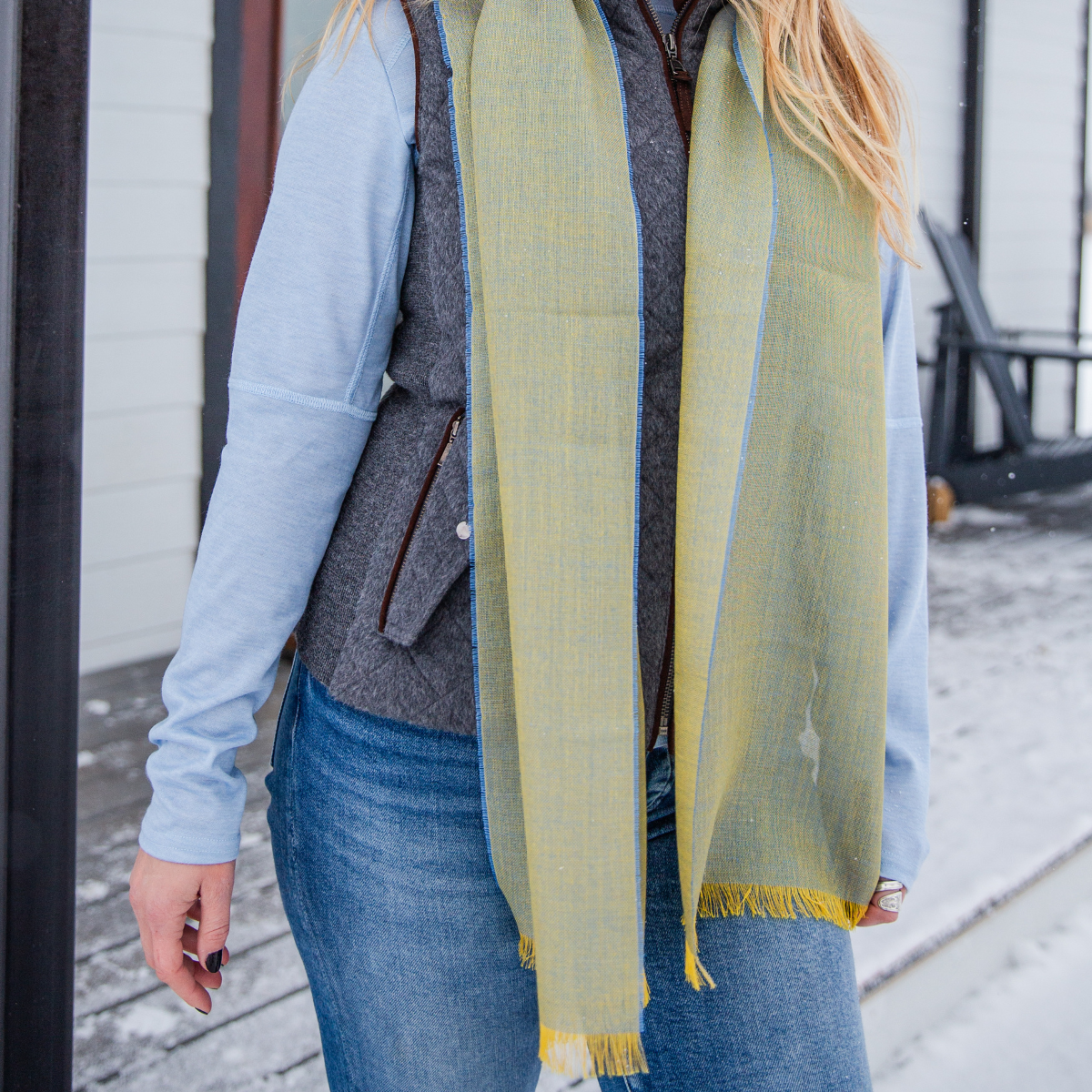 Woman in jeans outside wearing an alpaca sscarf with silk blue and yellow colors