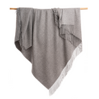 An Alpacas of Montana soft cozy luxury warm medium light charcoal gray blanket with a tasseled edge.