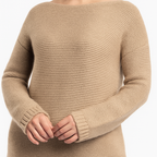 Close-up photo of a beige ribbed knit sweater with a boat neckline and long sleeves, showing the soft texture and detailed stitching while the model gently clasps her hands.