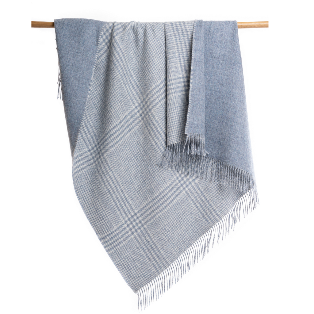 An Alpacas of Montana soft cozy luxury warm dusty blue sky plaid blanket with a tasseled edge.