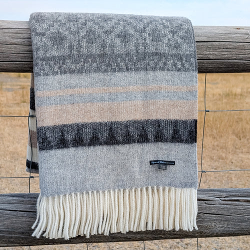 Striped blanket with fringes draped over a wooden railing