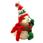 Plush toy penguin wearing a red and green crochet hat and scarf on a white background