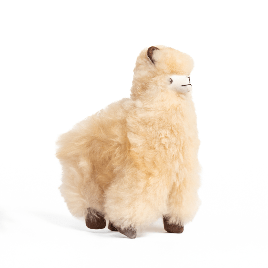A plush toy resembling an alpaca with beige fleece, black eyes, and a brown nose.