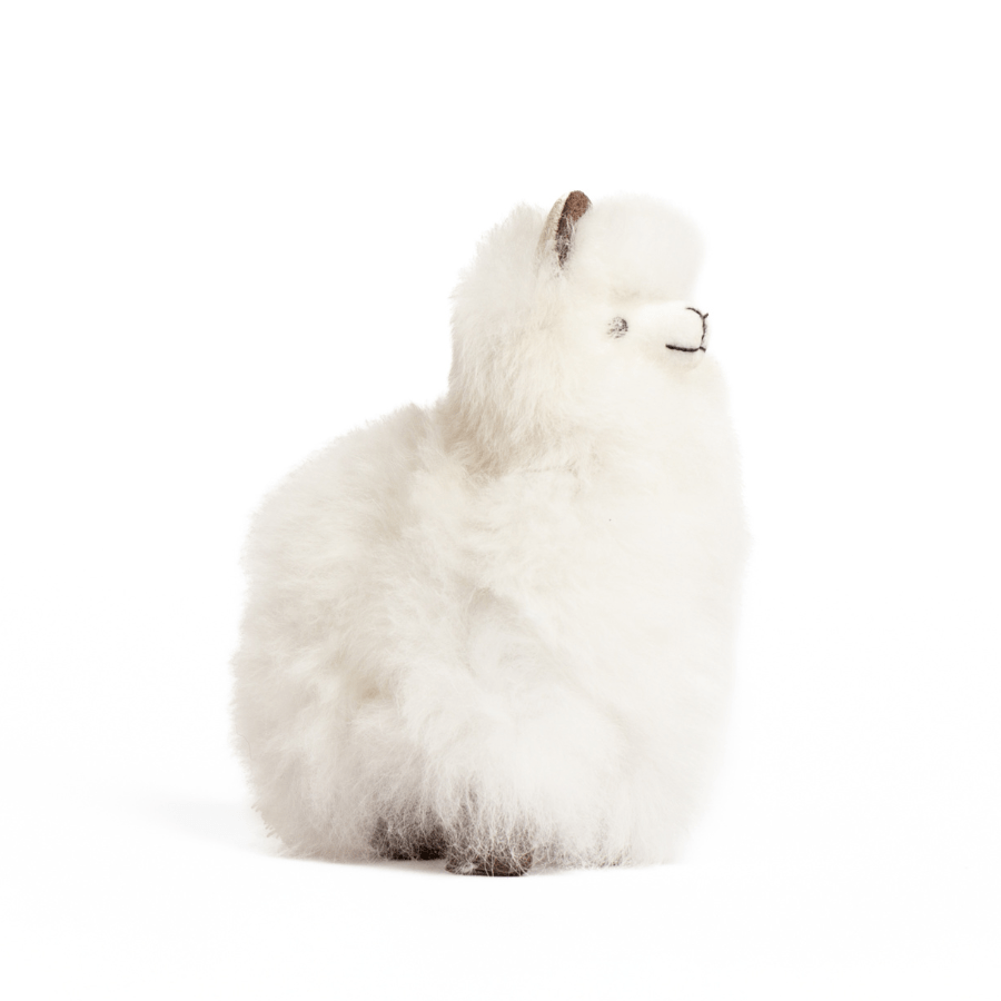 A white plush toy resembling an alpaca with beige fleece, black eyes, and a brown nose.