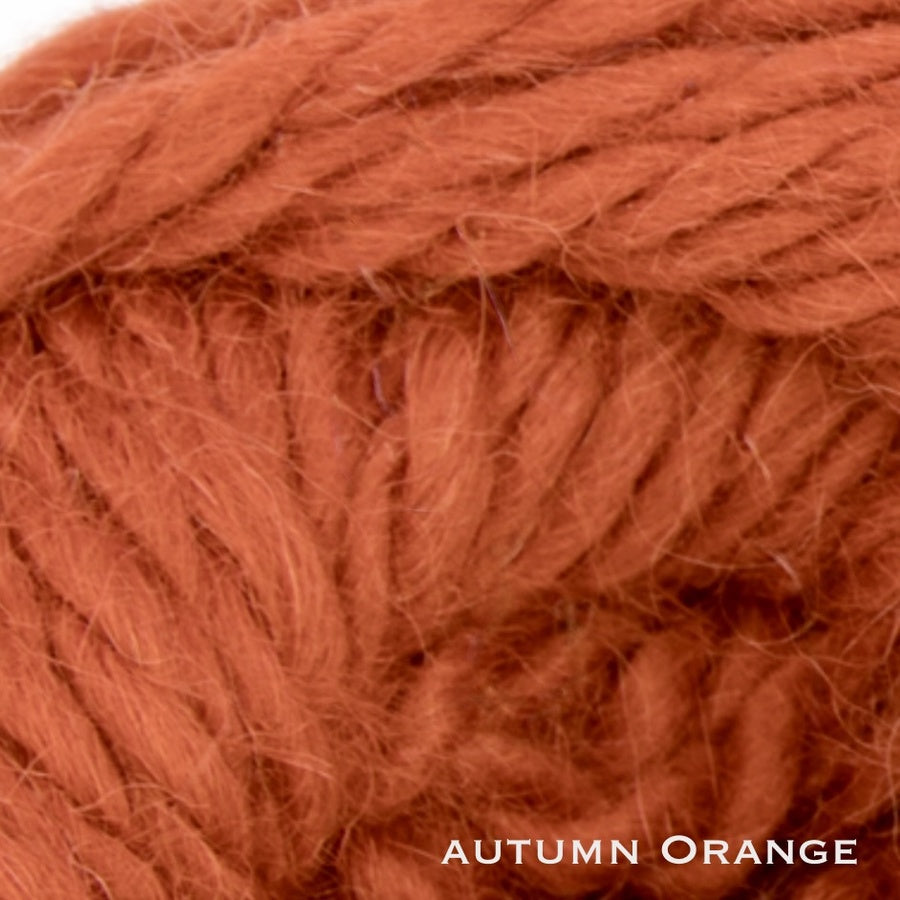 Close-up of a ball of orange baby alpaca yarn labeled 'Autumn Orange'. Used for bulky knitting.