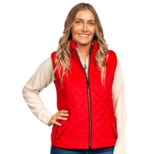 A woman wearing a gray alpaca wool vest with a hood, over a white and brown top, standing against a white background.