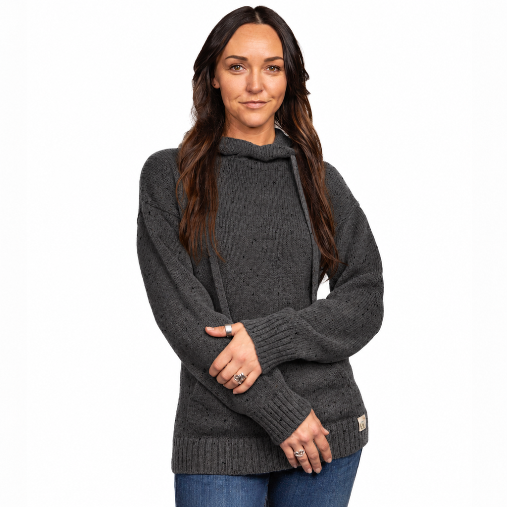 A woman wearing a dark gray knit sweater with a high mock neck and drawstring, paired with blue jeans, against a plain white background.