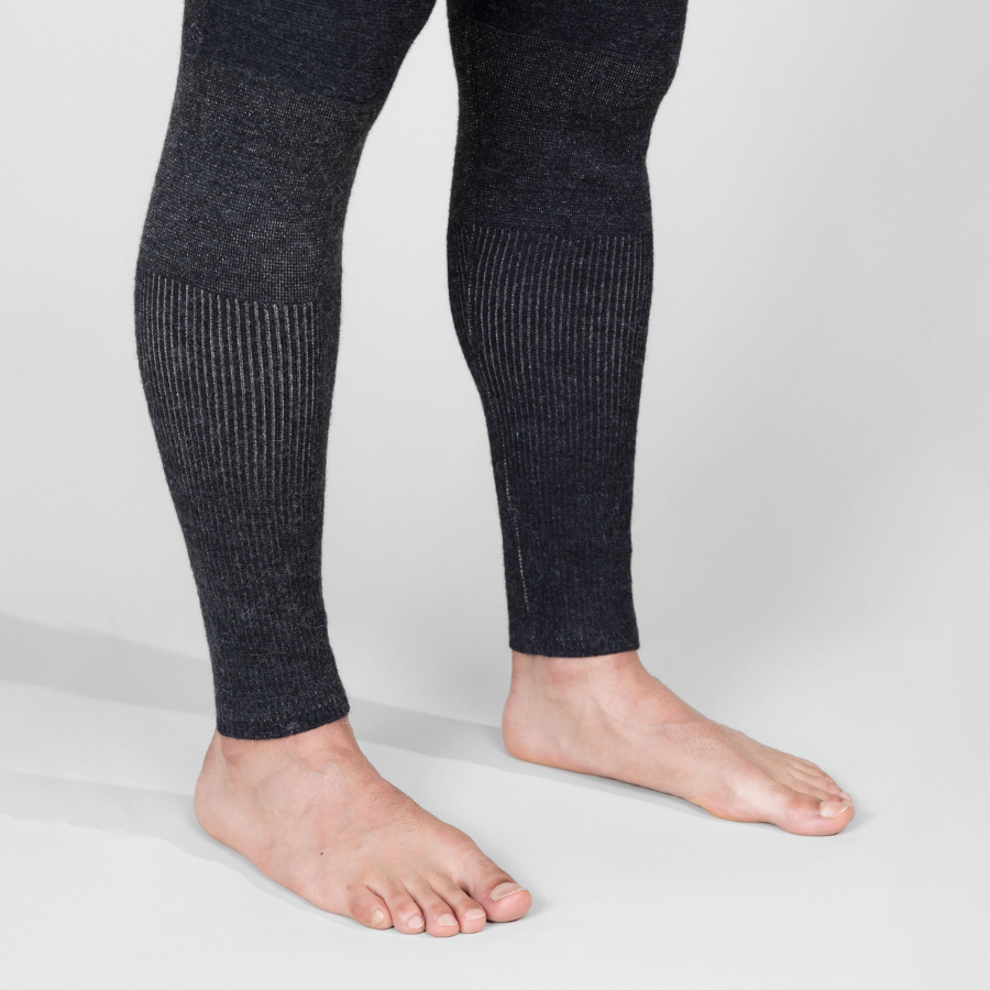A cose up photo from the knees down of a person standing against a white background wearing a pair of the Alpacas of Montana warm underlayer cozy comfortable thermal moisture wicking long johns winter outerwear heavyweight antimicrobial alpaca wool men's red and black base layer bottoms for skiing, snowboarding, ice fishing, hunting, camping, arctic, travel