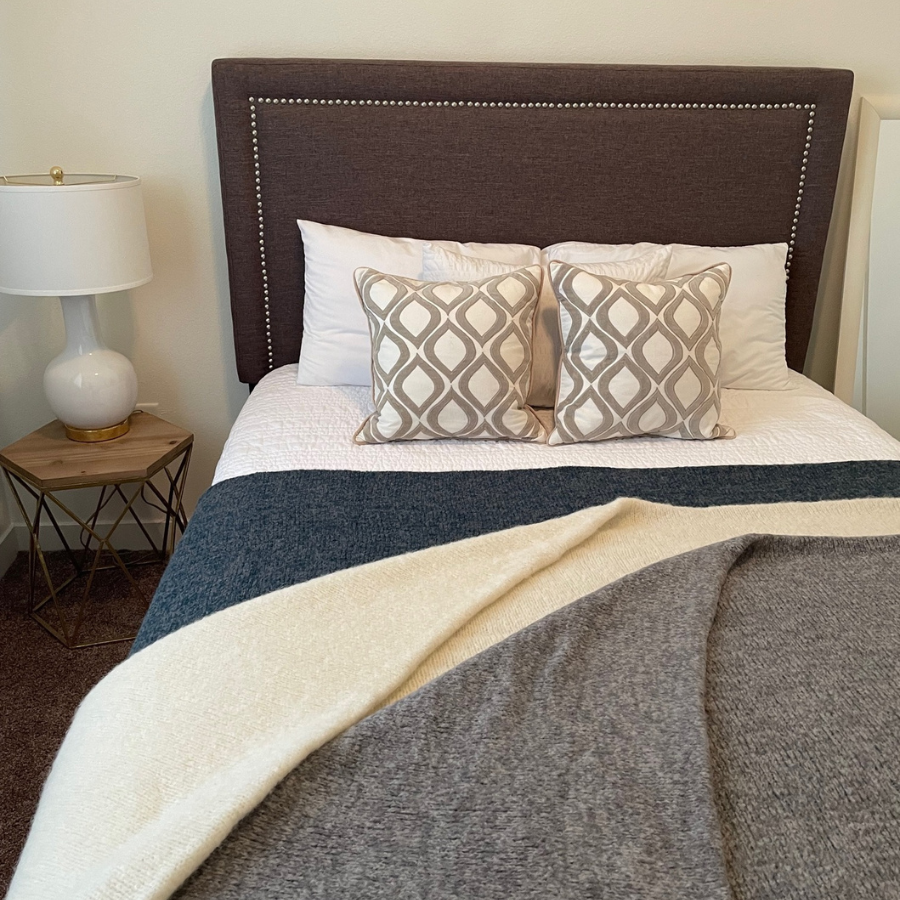 Blue, white and gray alpaca blankets on king size bed with brown headboard