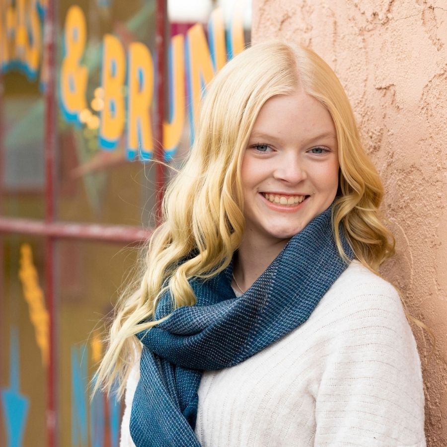 woman smiling wearing blue alpaca wool shawl as a scarf