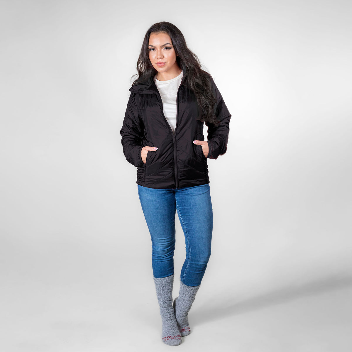 Front facing woman wearing black alpaca single layer winter jacket with blue jeans and winter alpaca socks