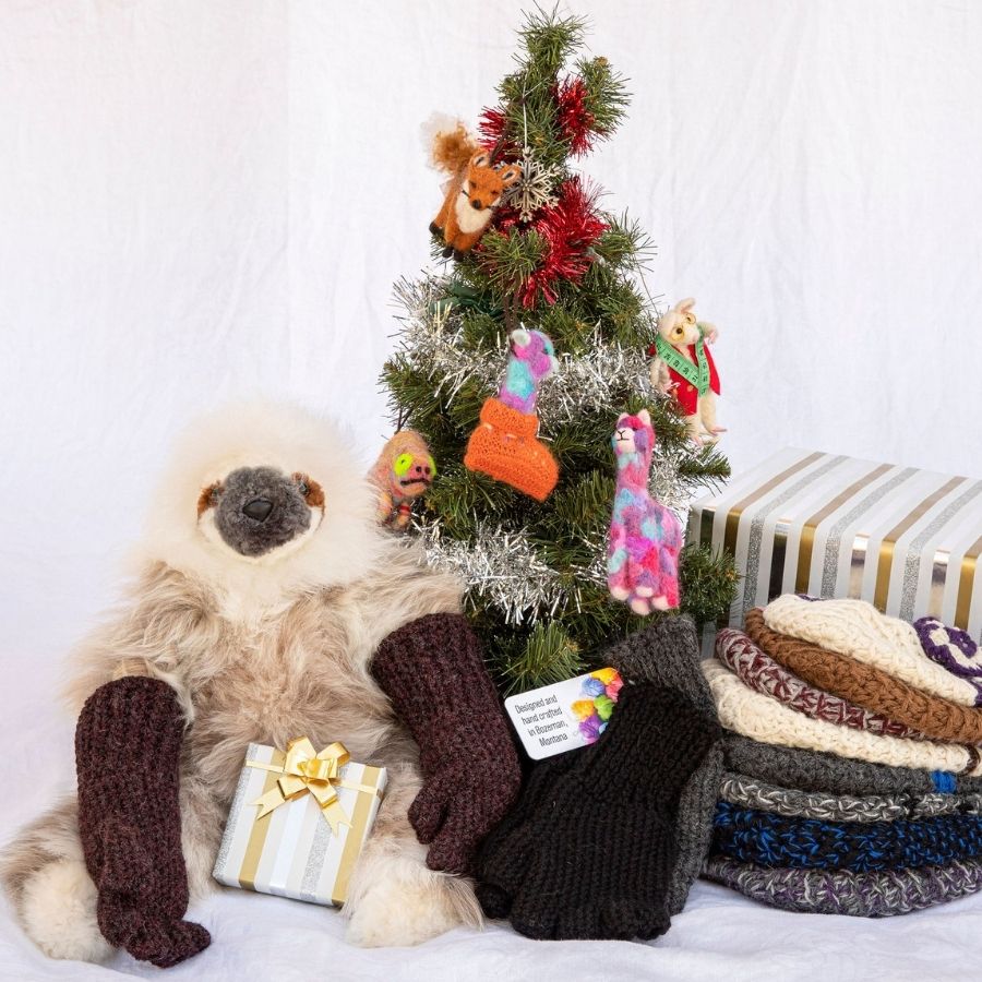 alpaca wool sloth wearing alpaca wool fingerless gloves sitting in front of a christmas tree